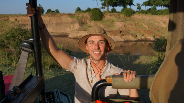 man wearing a hat climbing into a safari jeep at sunset